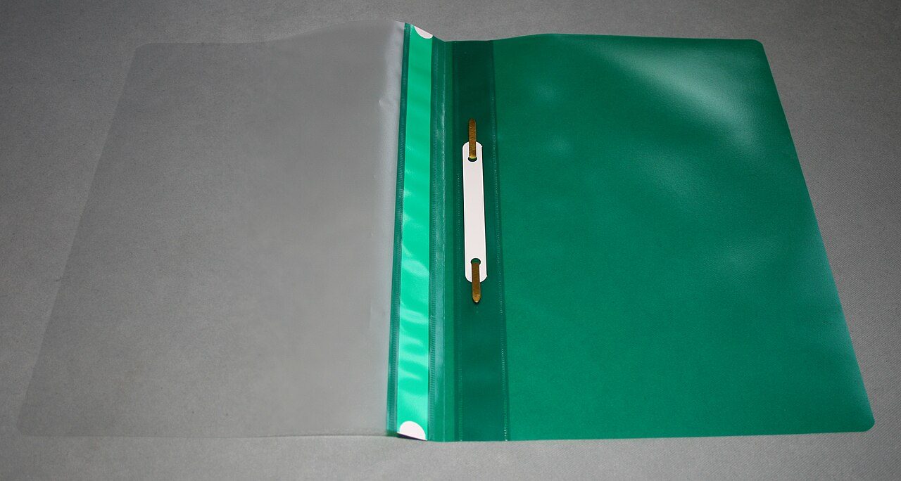 A green plastic folder with a clip along the spine