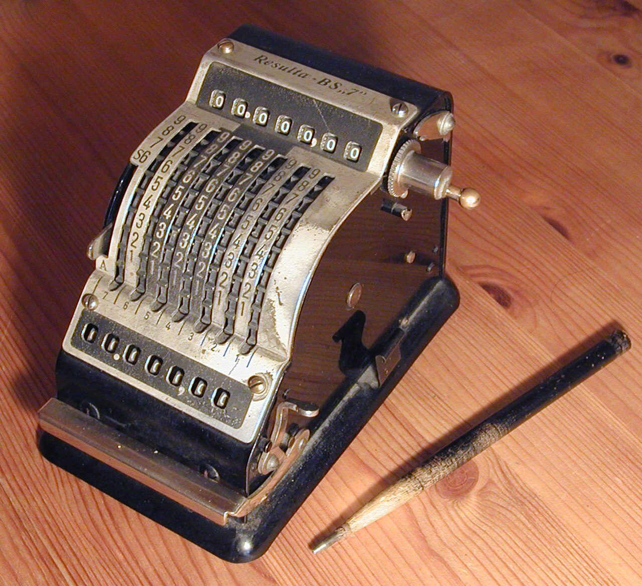 A mechanical calculating machine with a pencil beside it
