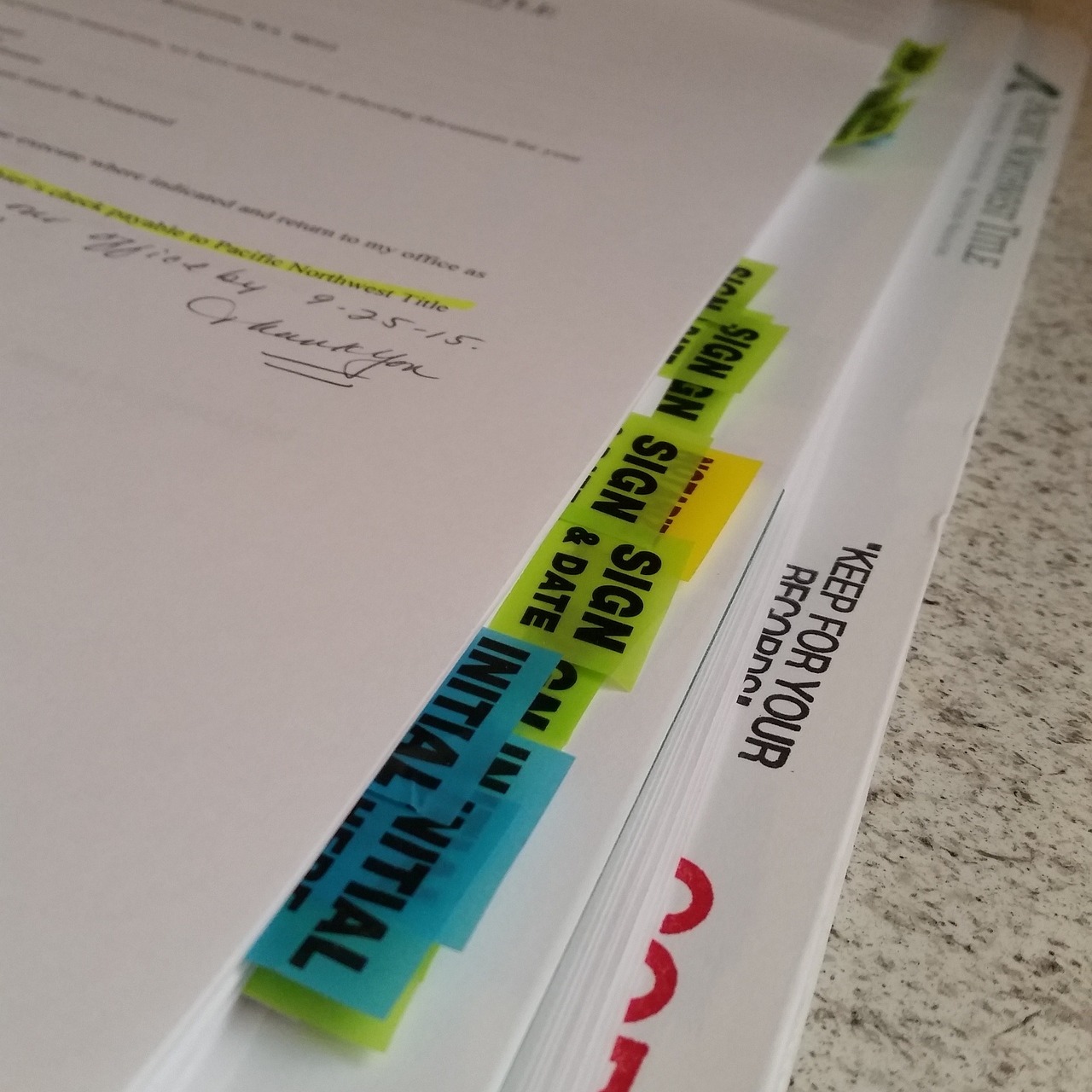 A signed closing packet with sign-here tabs and a handwritten name