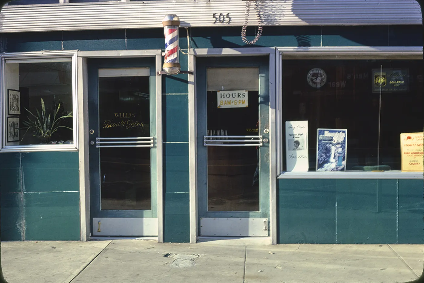 The front door of a beauty shop, with the hours posted on the glass.