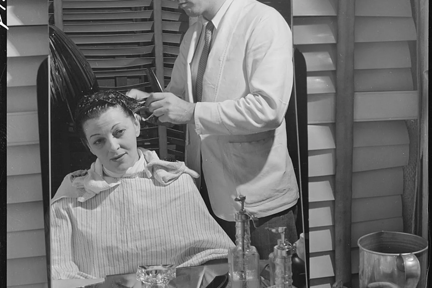 A stylist cutting hair, seen in the mirror with the guest in the chair.