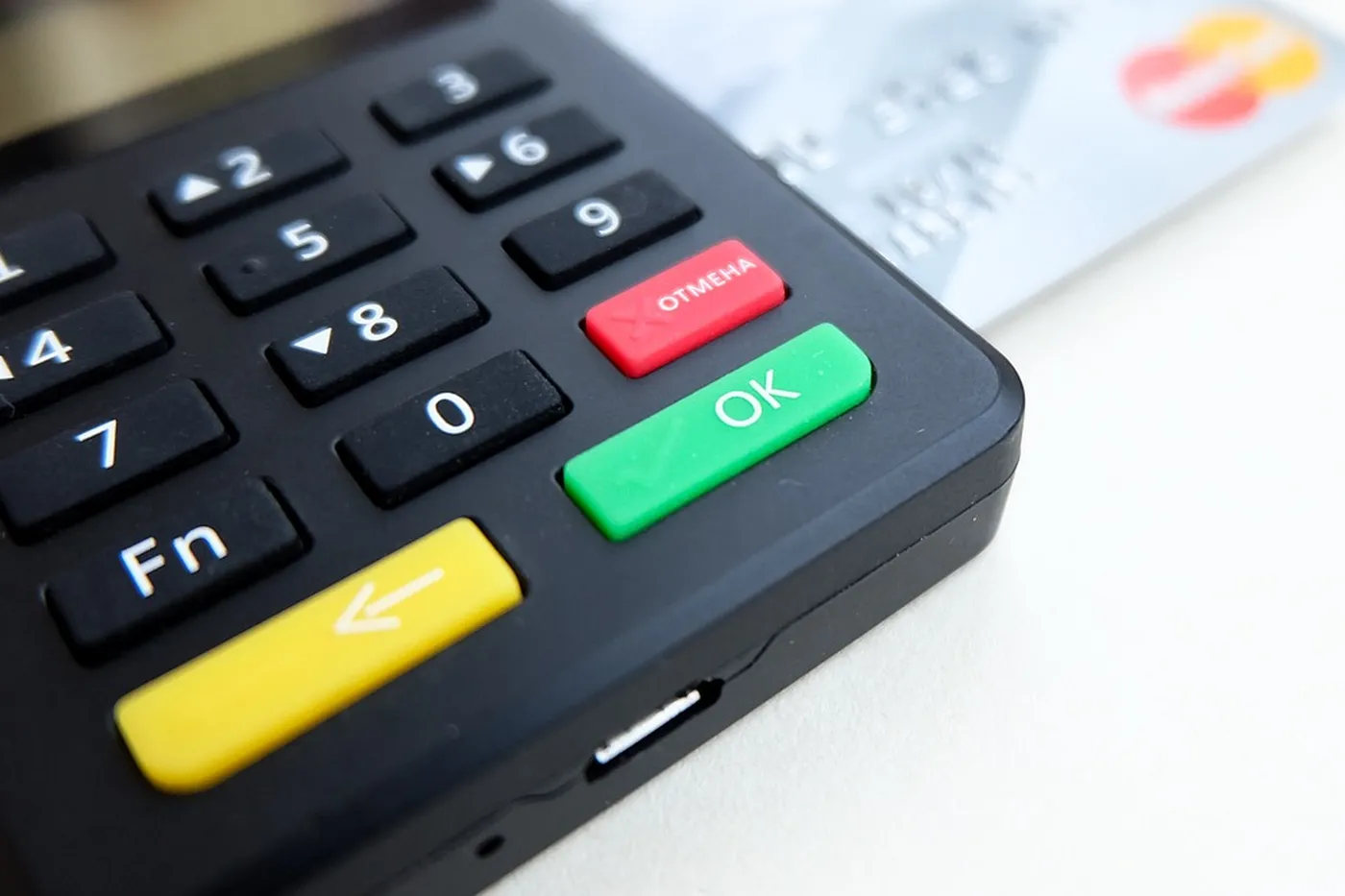 A card terminal keypad with a payment card lying beside the machine.