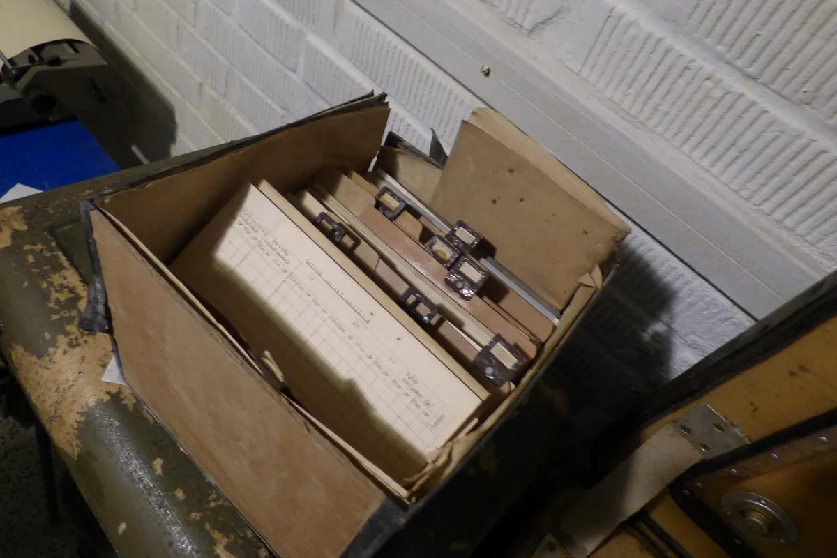 An open box of paper folders on a worn table