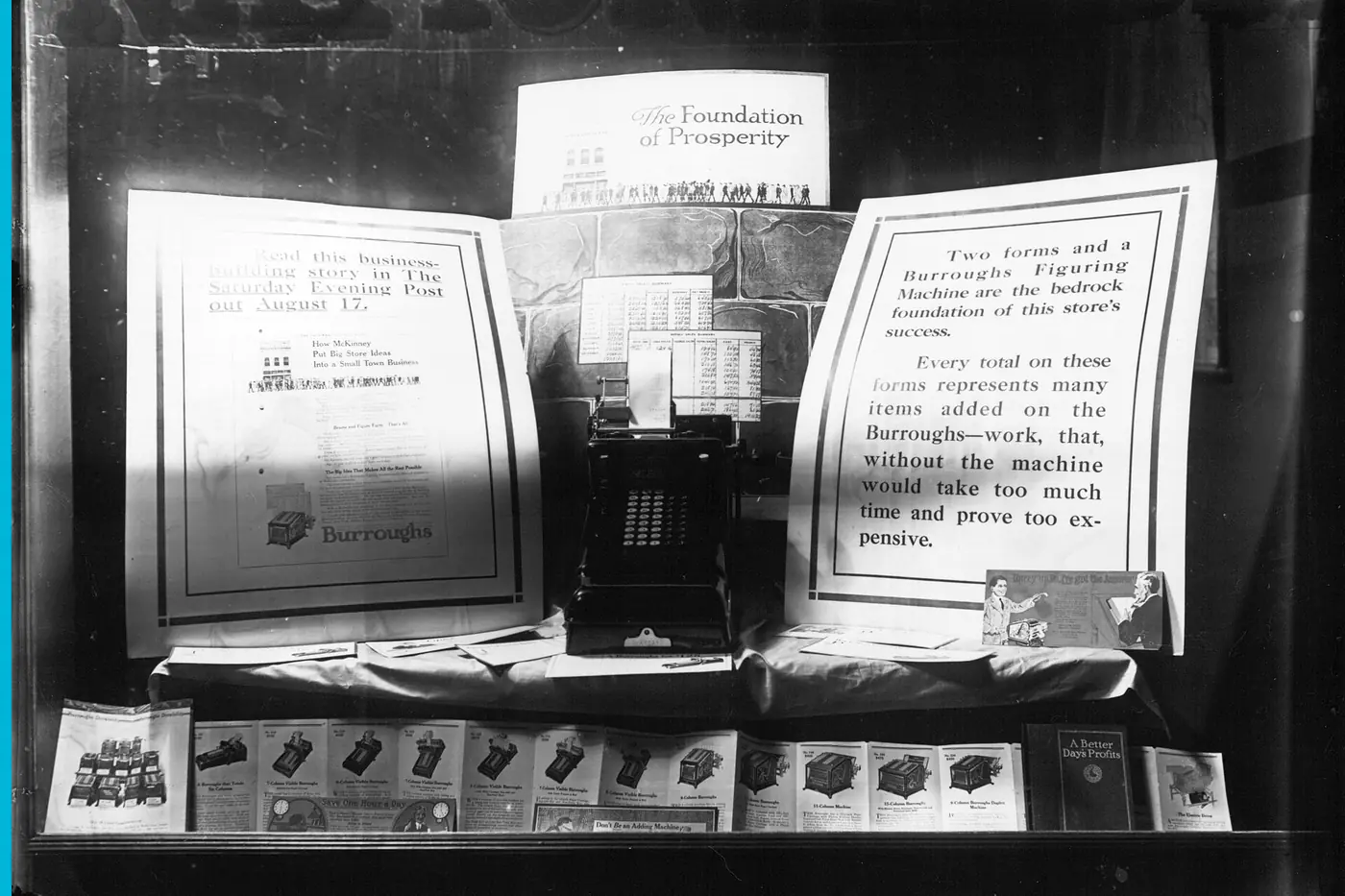 An adding machine in a bank window, papers standing beside it