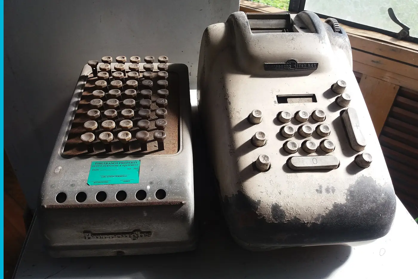 Two adding machines side by side, keys and a paper roll