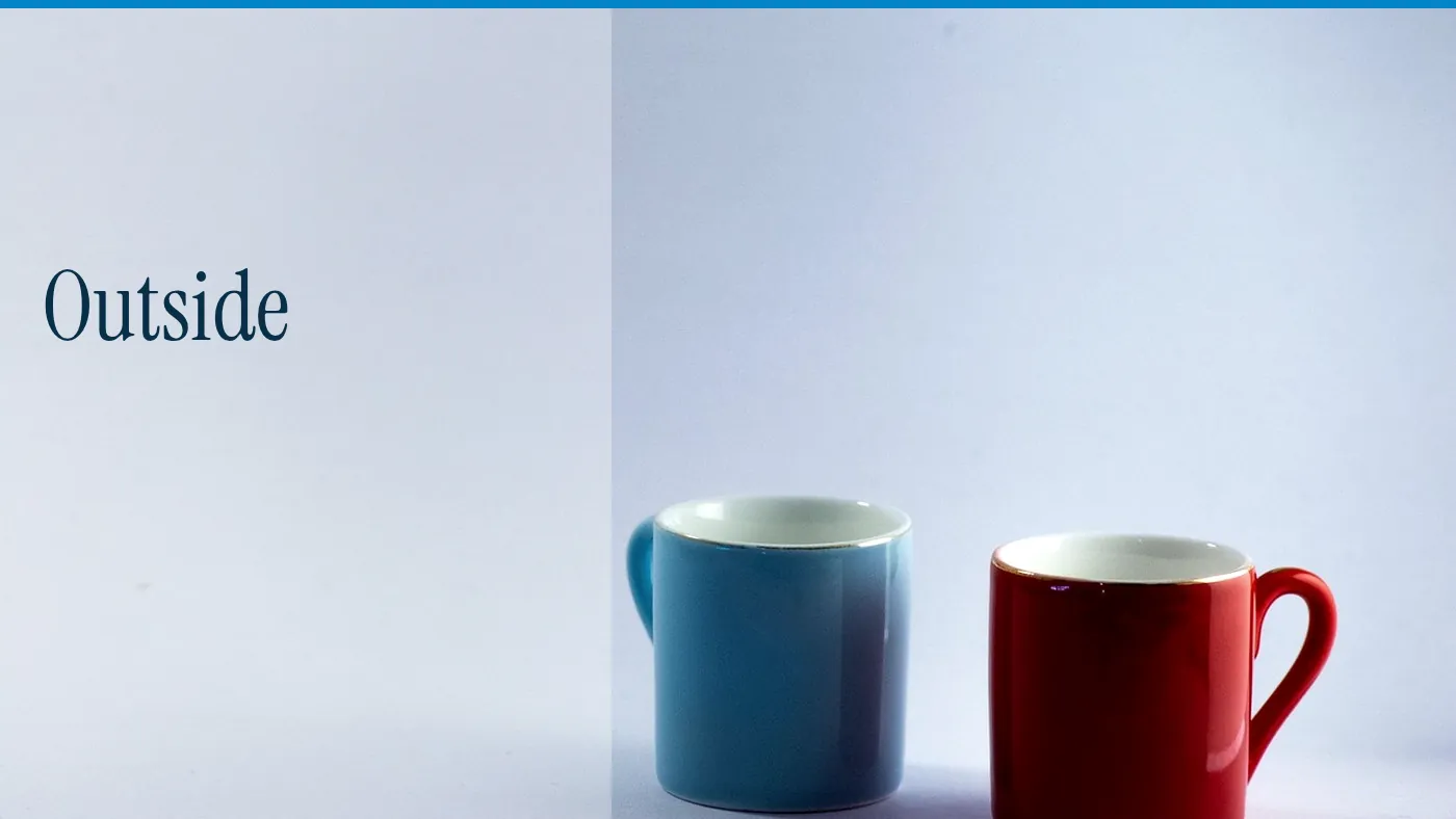 A blue cup and a red cup on a pale ground, with the word Outside in large type