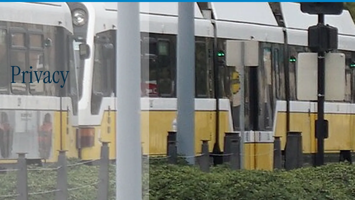 A yellow and white train at Deep Ellum station, with the word Privacy in large type