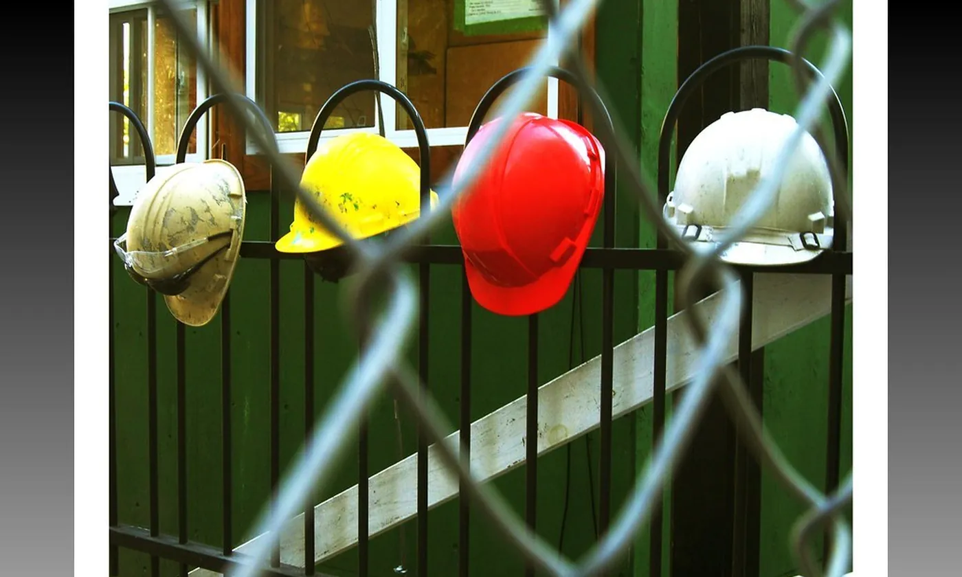 Hard hats hung on a fence at the end of a work day