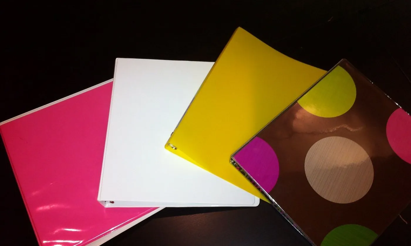 Four closed ring binders fanned out on a dark table