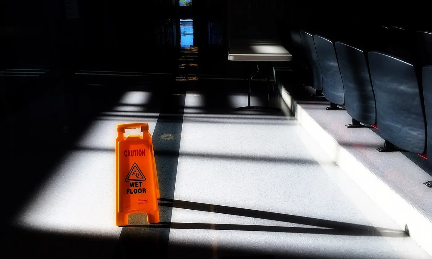 A wet floor sign standing in a hallway as sunlight comes back through the windows