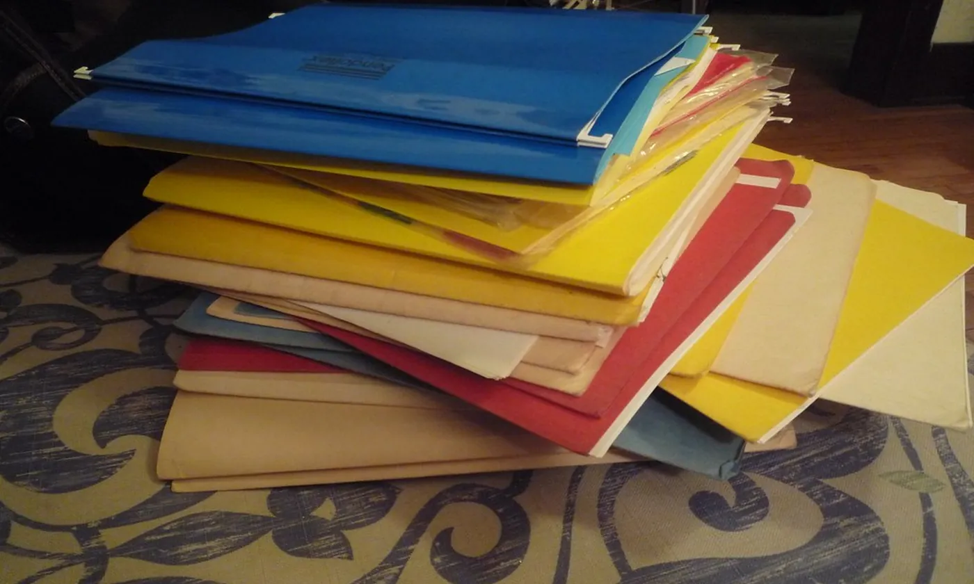 A loose stack of colored file folders on a table