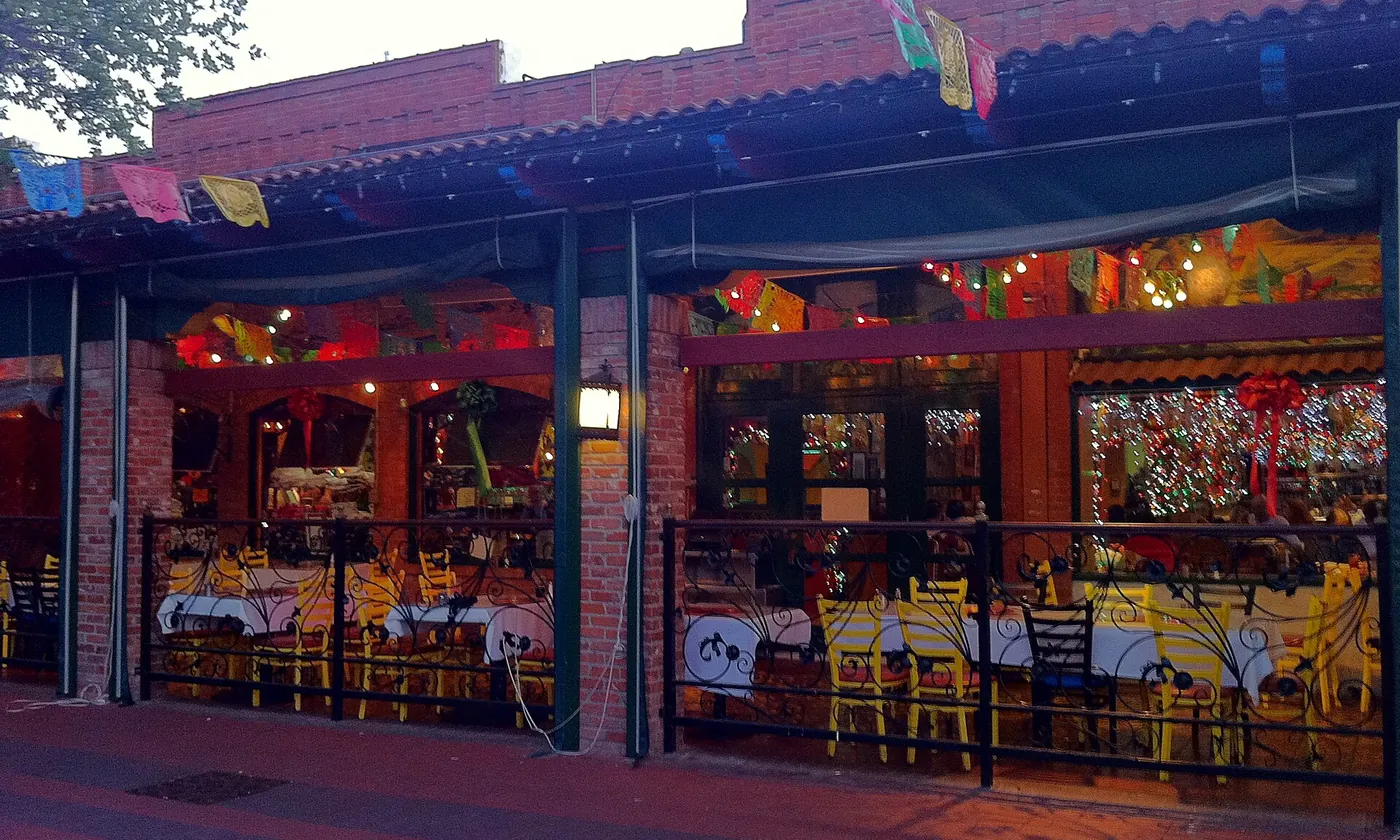 The lit front of Mi Tierra at Market Square in the evening, papel picado over the door