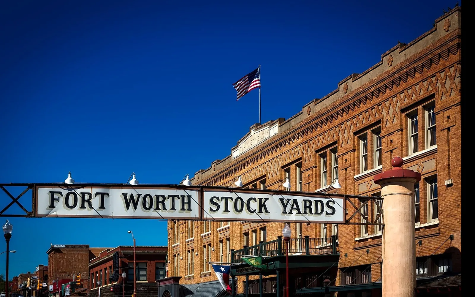 The Fort Worth Stockyards entrance, the Texas flag over the sign, brick buildings behind it