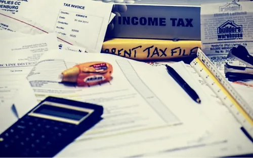 A table with a tax invoice, a binder, and a calculator