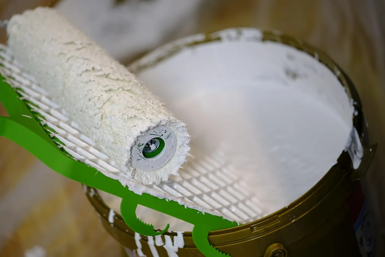 A roller resting on a paint bucket