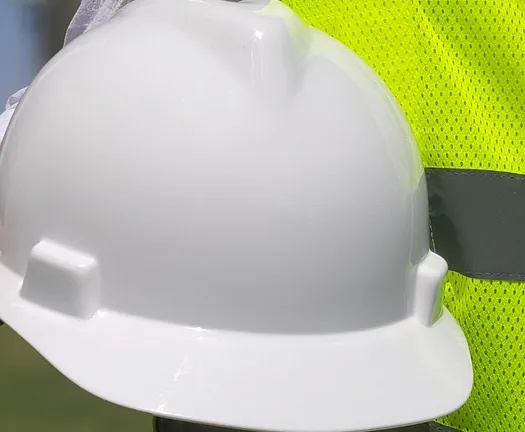 A white hard hat against a high visibility vest