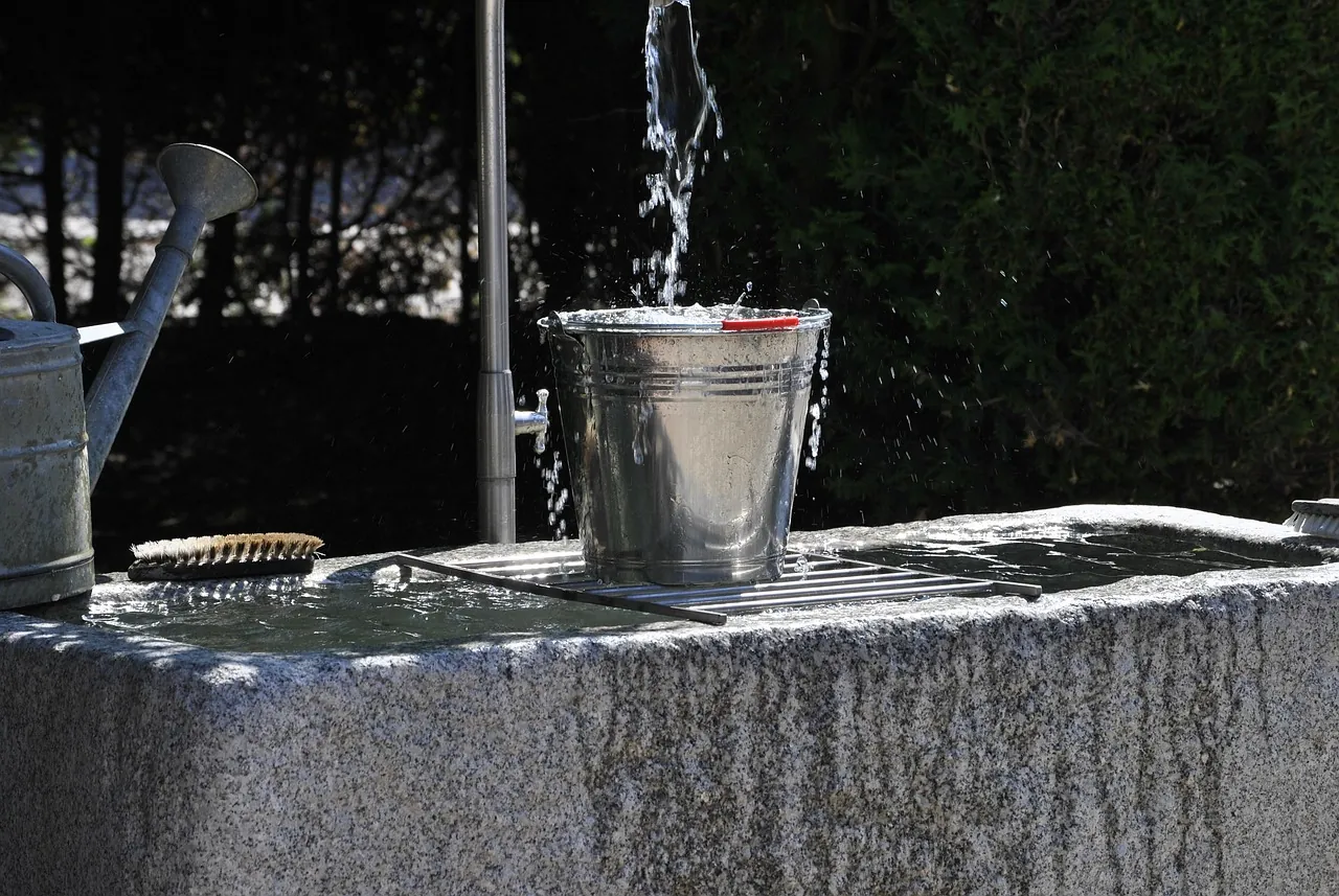 A metal bucket under a running tap