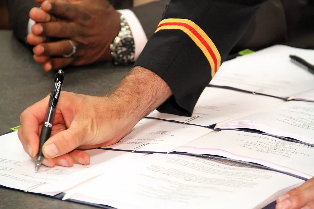 A person signing a stack of agreements