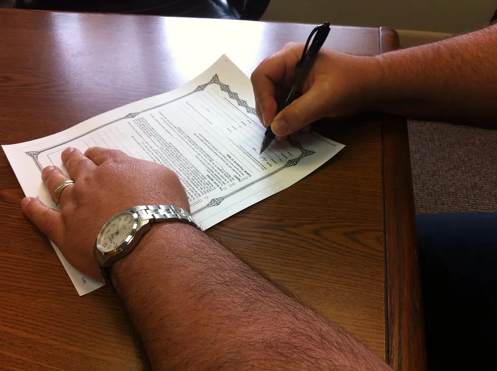 Hands signing a printed form on a table