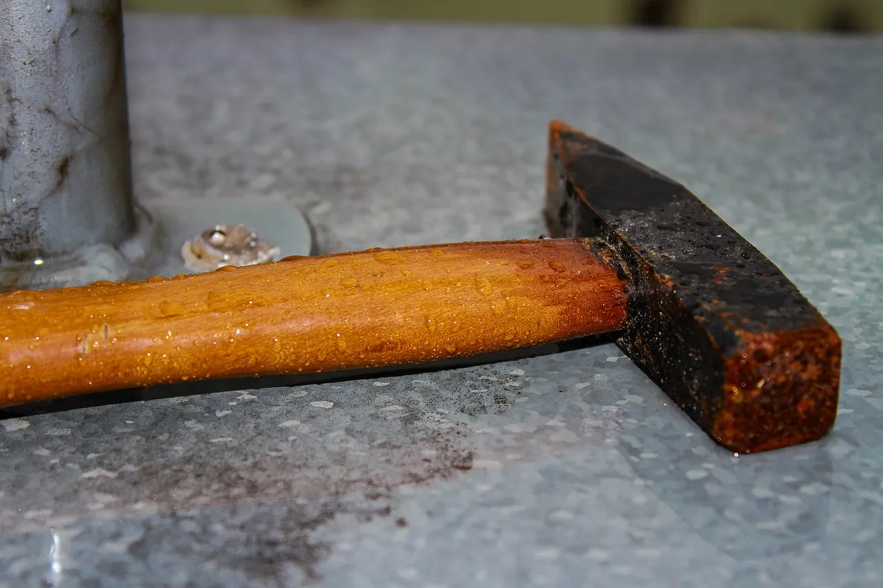 A hammer resting on a metal bench