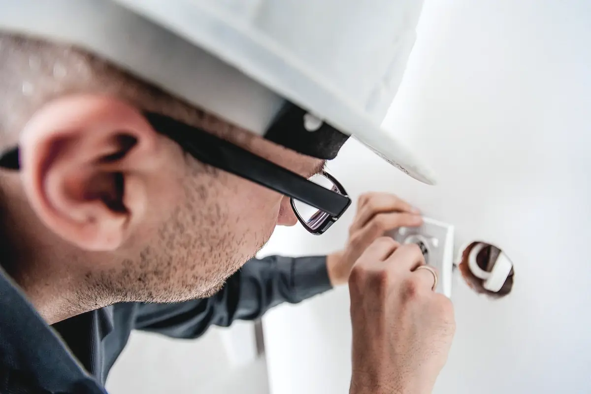 An electrician in a hard hat working at an outlet