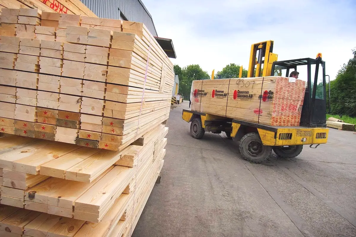 Stacks of lumber in a yard beside a forklift