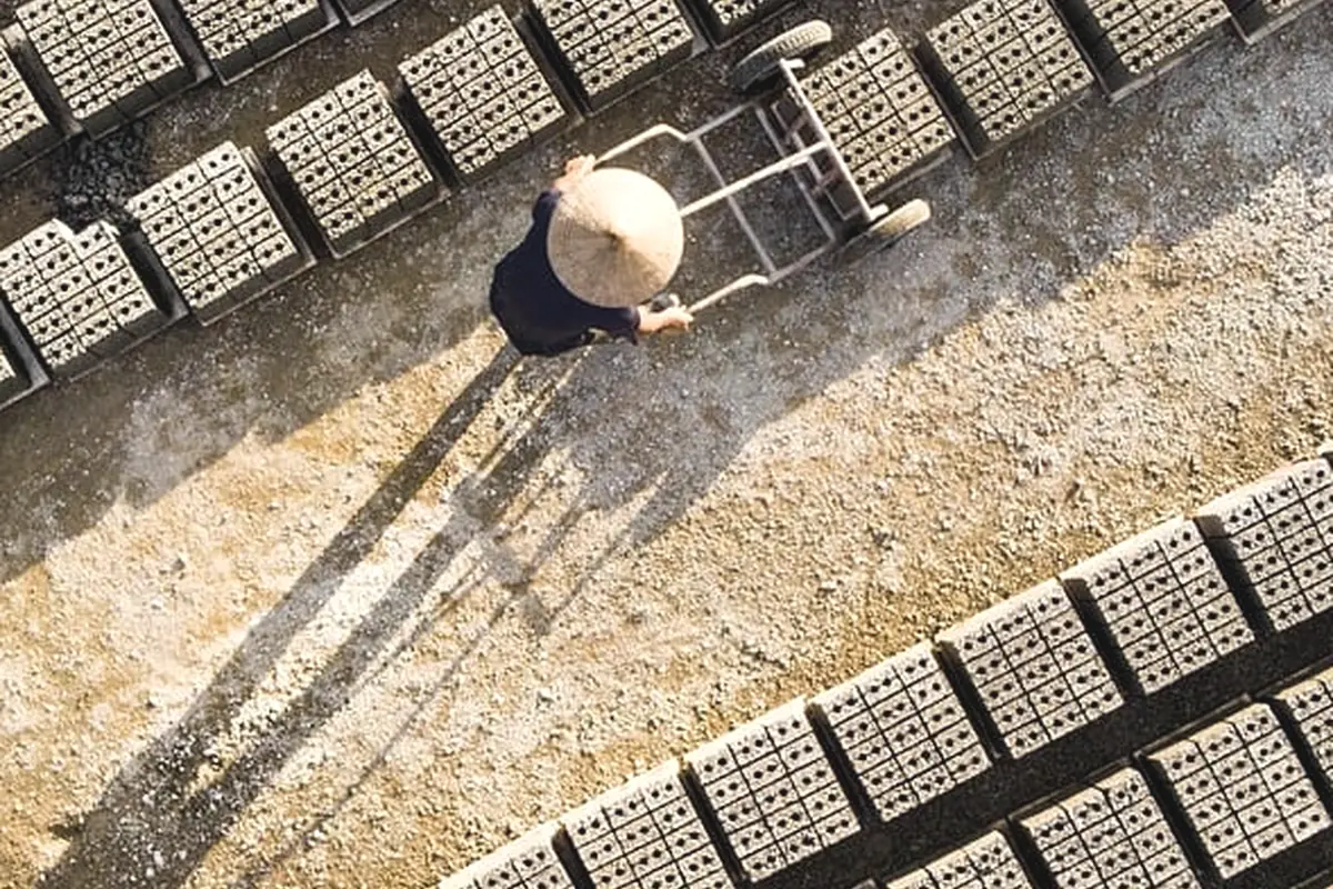 A worker moving blocks across a material yard