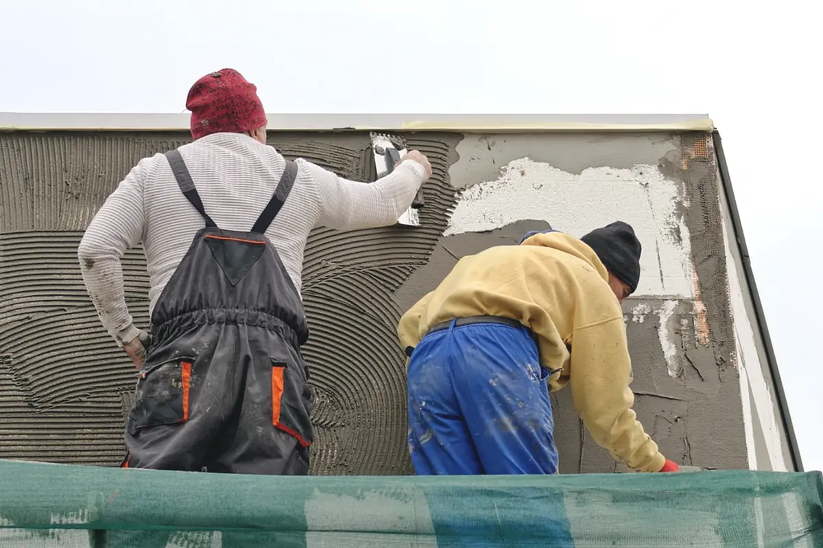 Two workers finishing a wall with a trowel