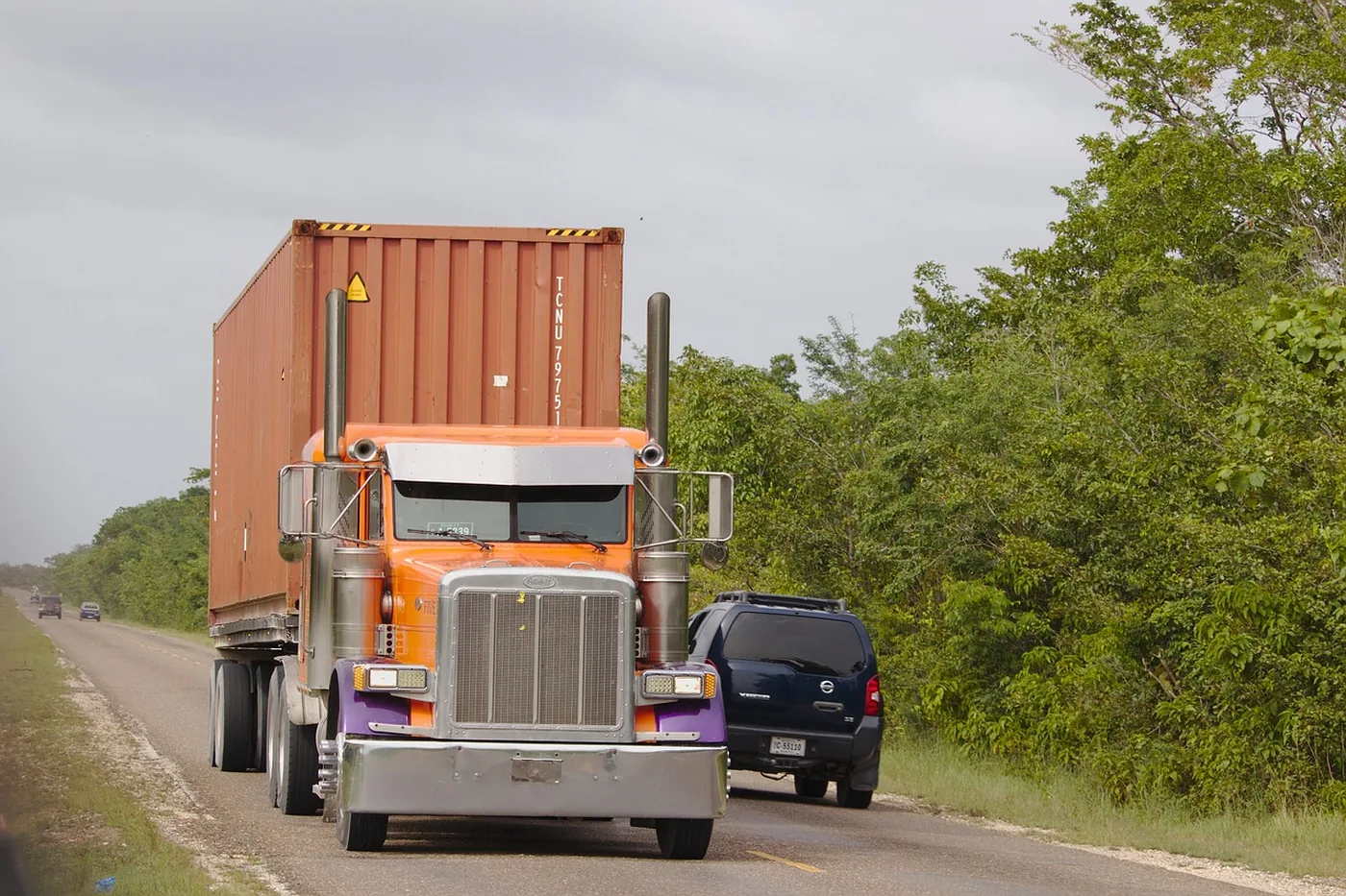 An orange freight truck hauling a container