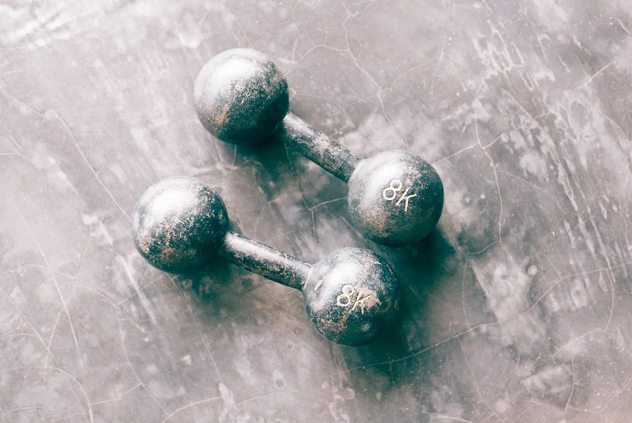 Two iron dumbbells on a worn concrete floor.