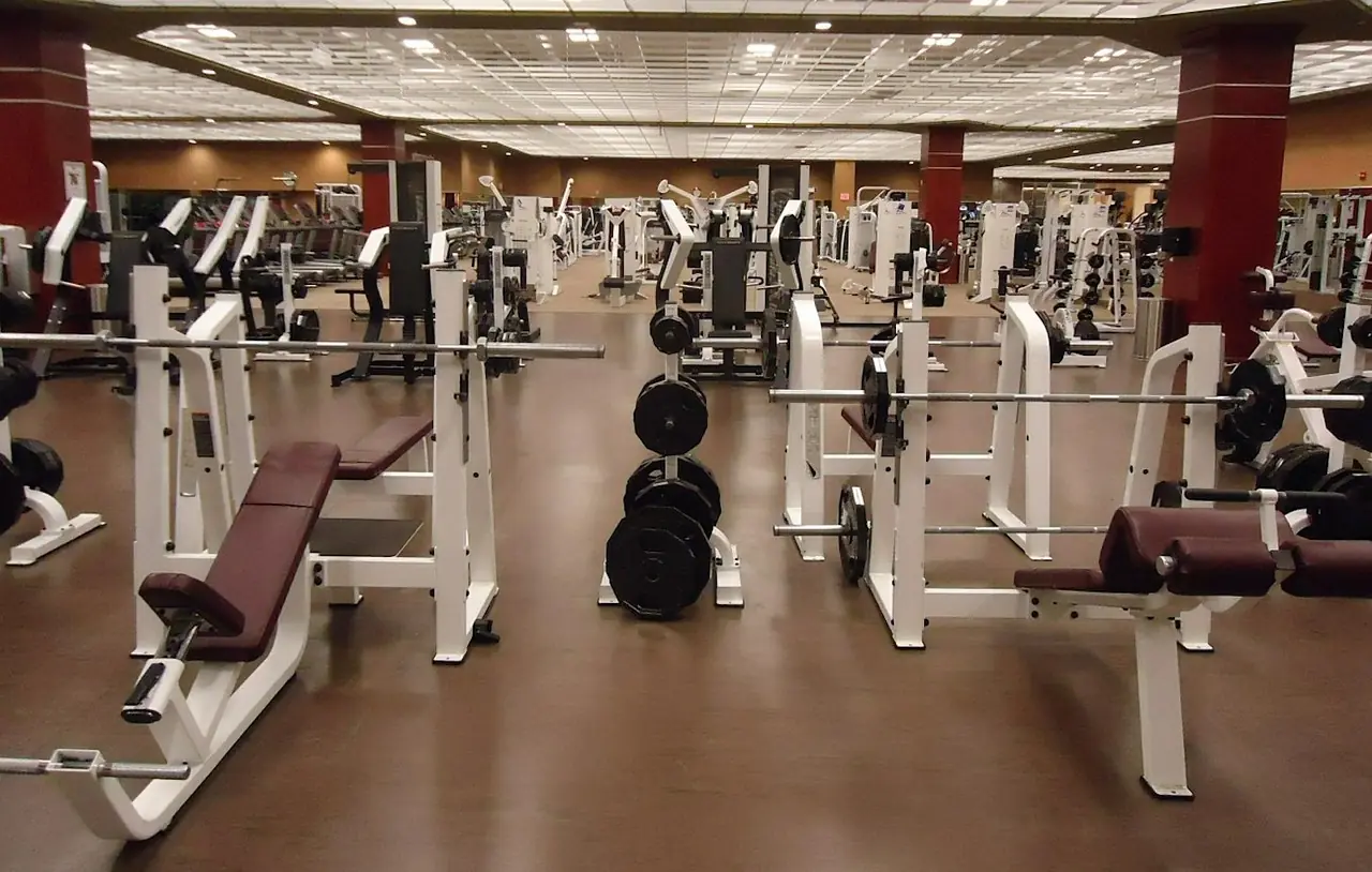 A weight room with machines in a row.