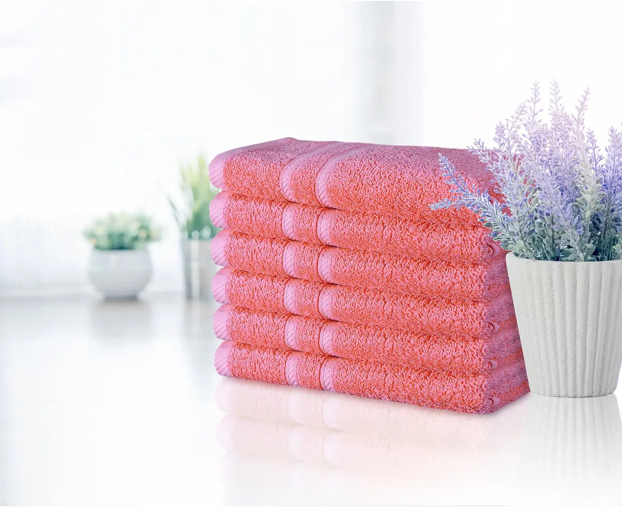 A stack of coral towels beside a small plant, with no writing.