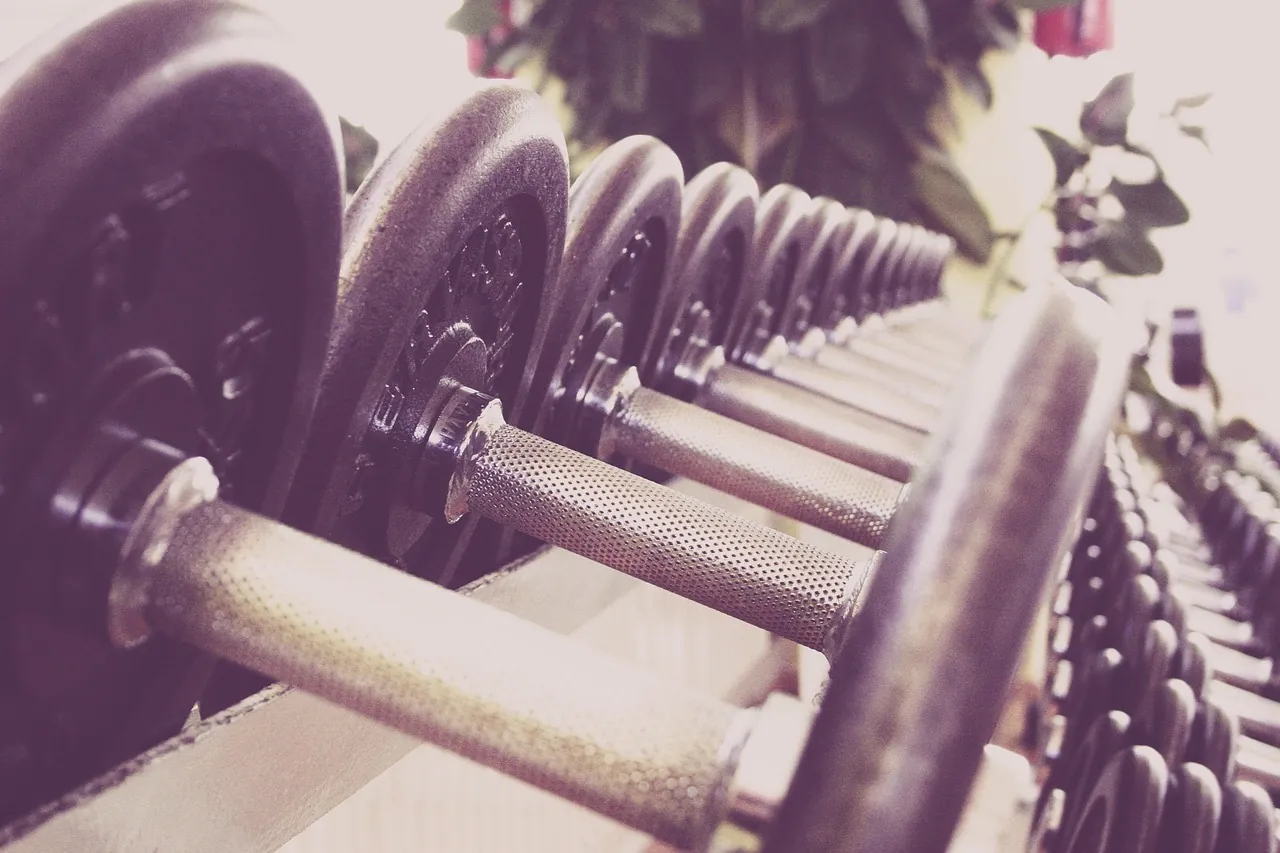 A rack of black dumbbells on a gym floor, with no sign and no city name.