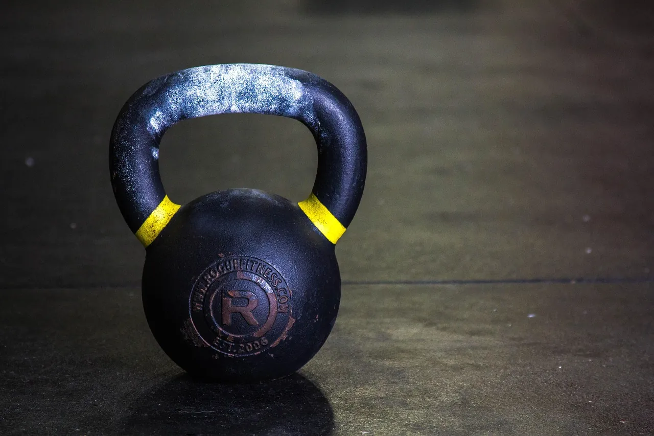 A black kettlebell on a gym floor, close and unbranded.