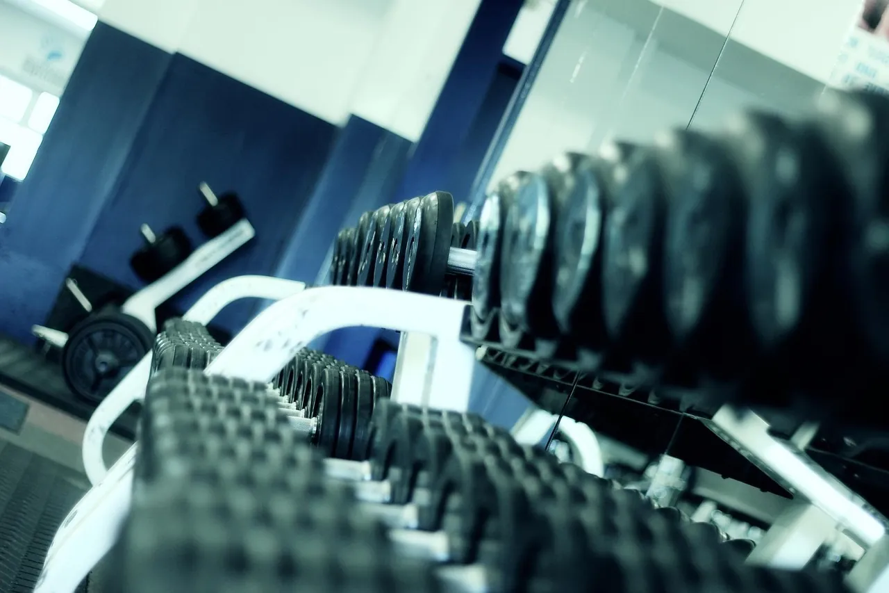 A person lifting a bar in a gym, seen from the side, with no readable logo.