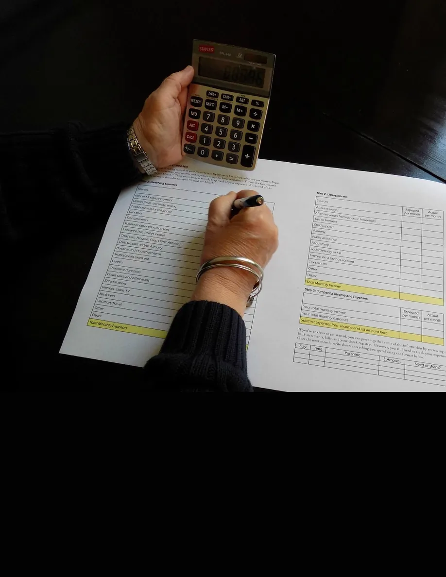 A calculator over a written budget, here because a balance that sat all spring is still a number to name.