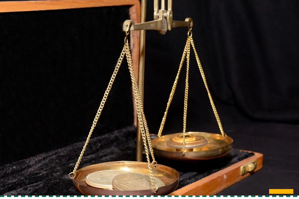 A brass balance scale with two pans on a dark wooden stand