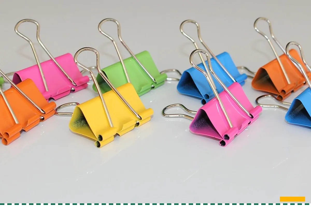 A row of colored binder clips on a white table