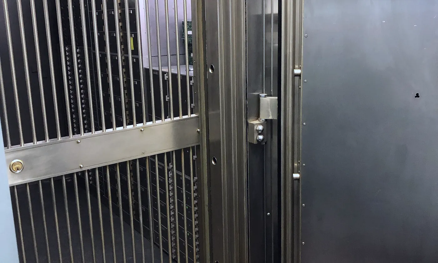 A vault door open beside a steel gate