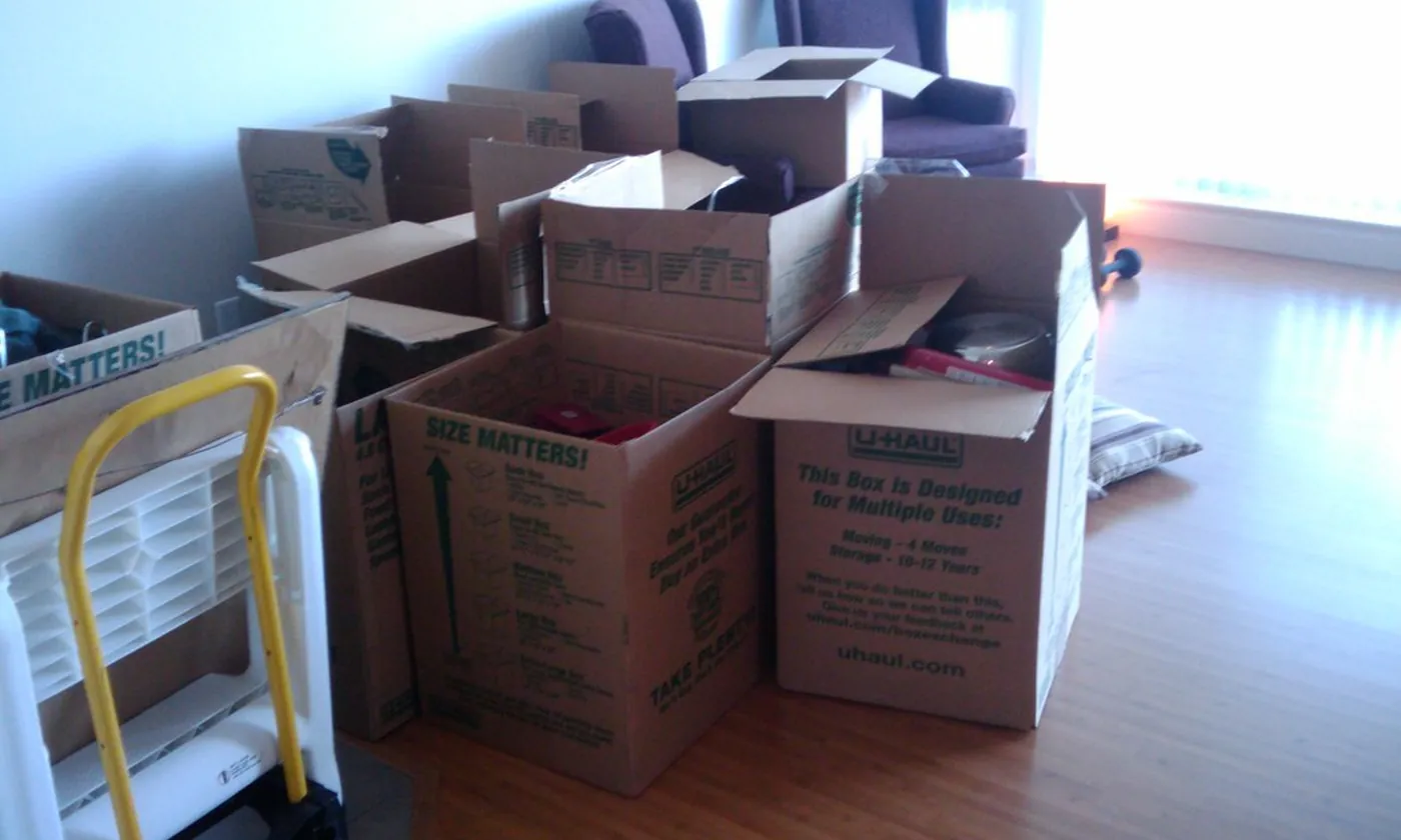 Moving boxes stacked in an empty room with a hand truck