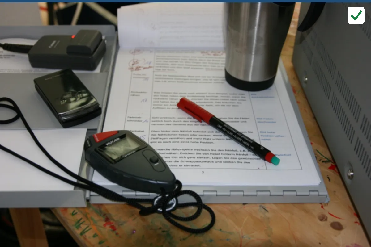 A table with printed notes, a red pen, a phone and a flask