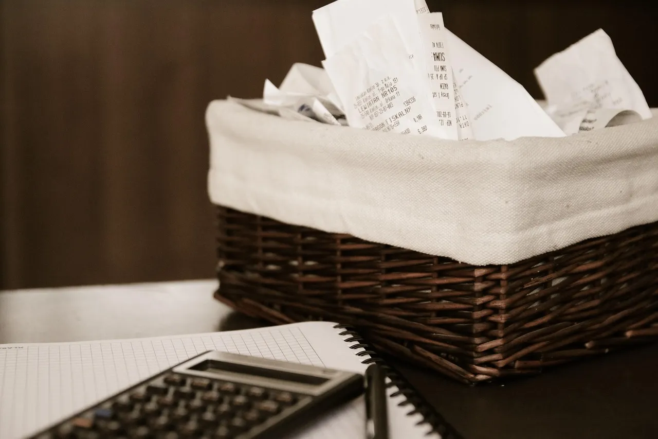 A calculator and a basket of paper receipts