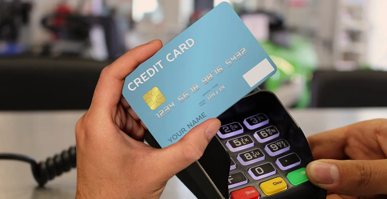 A hand holding a credit card at a payment terminal