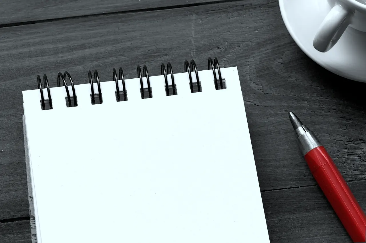 A sketchbook, a pencil, and a cup on a table