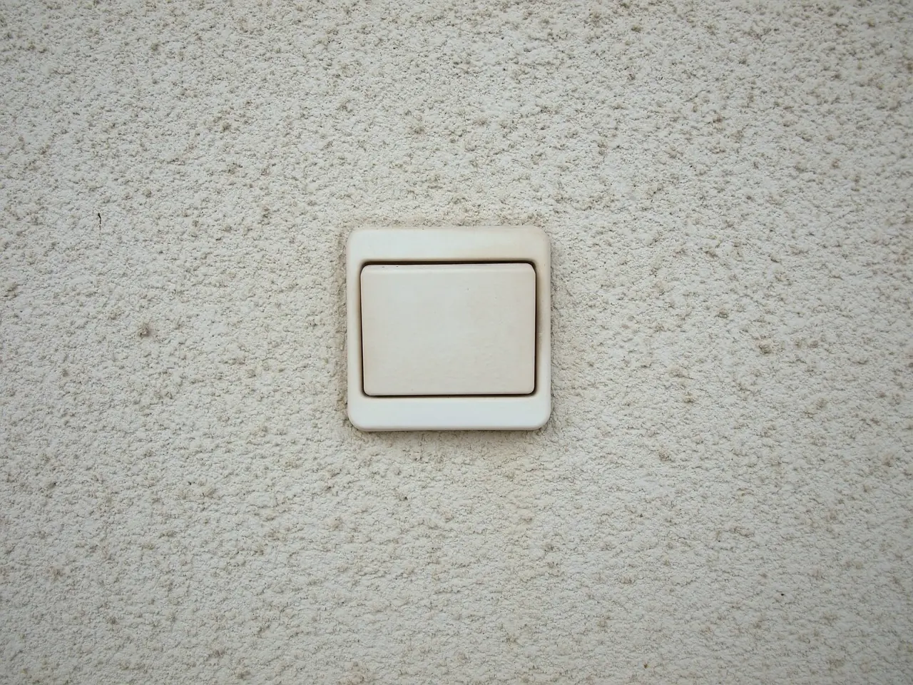 A white wall switch on a textured wall