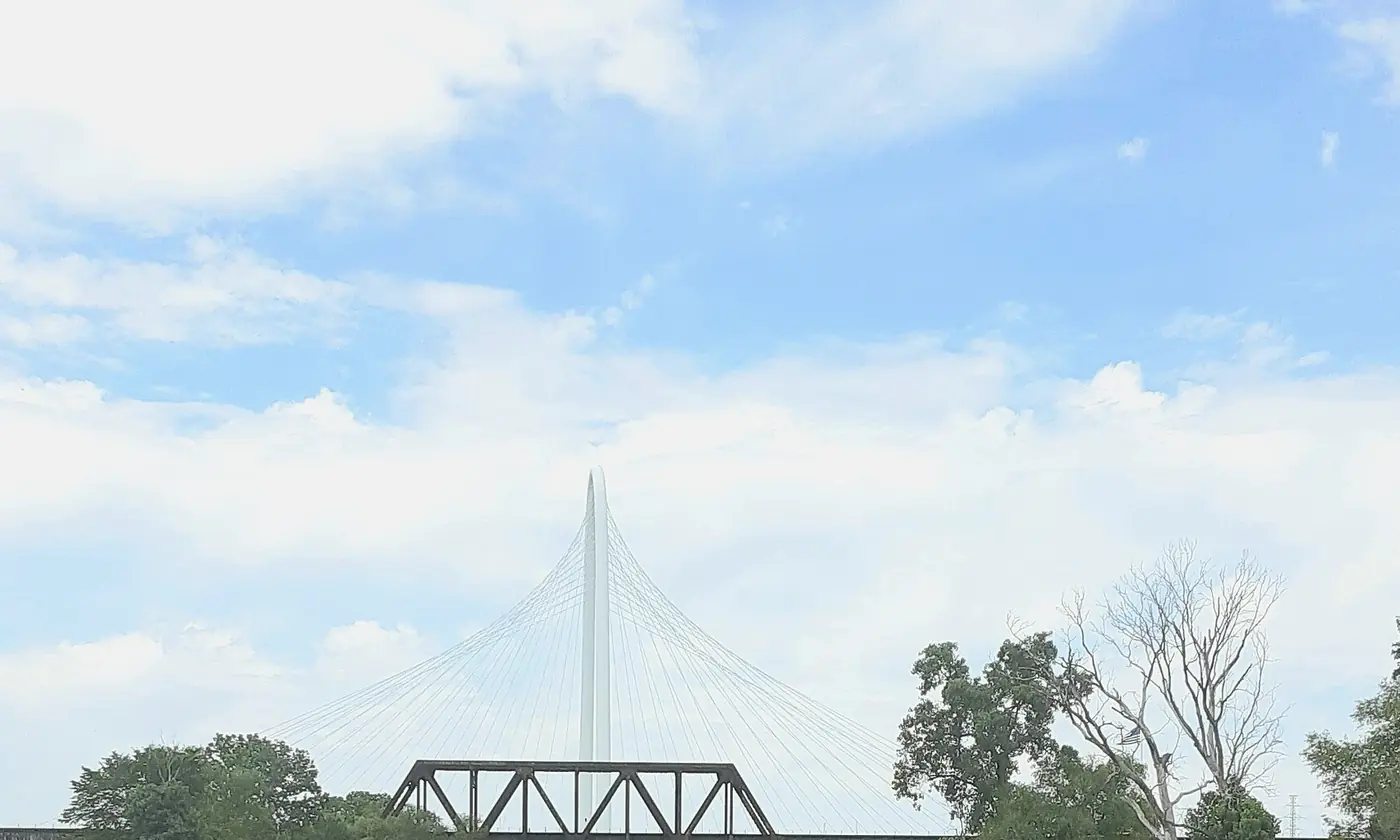 The Margaret Hunt Hill Bridge over the Trinity in Dallas, the white arch above the trees