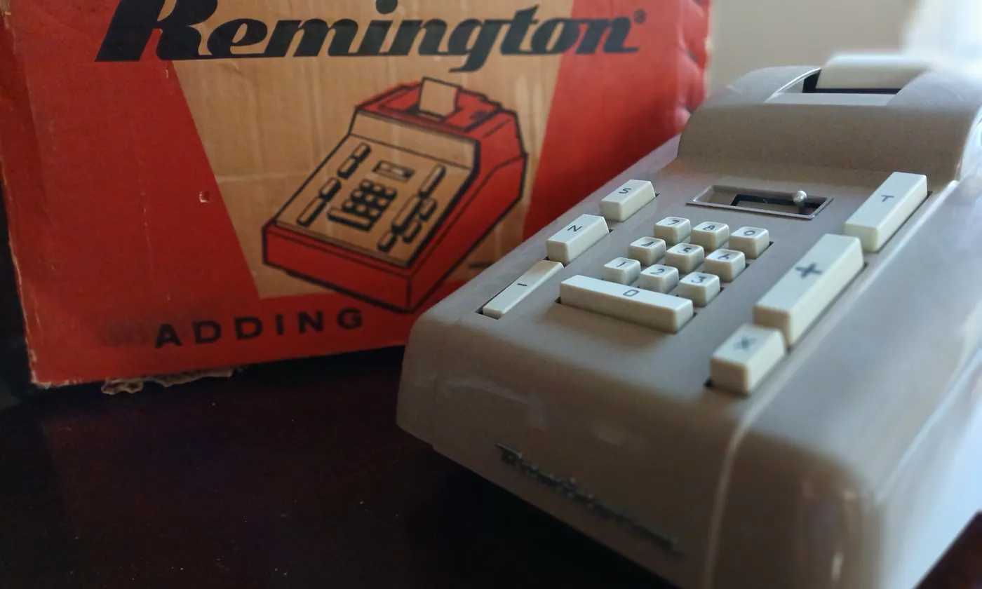 An adding machine with number keys and a paper tape