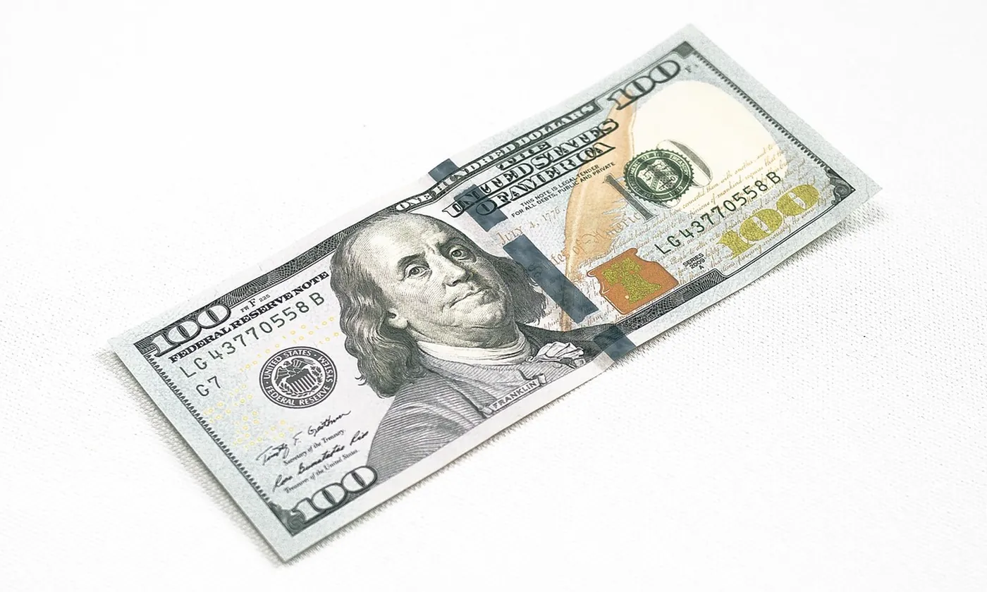 A United States one hundred dollar bill on a white surface