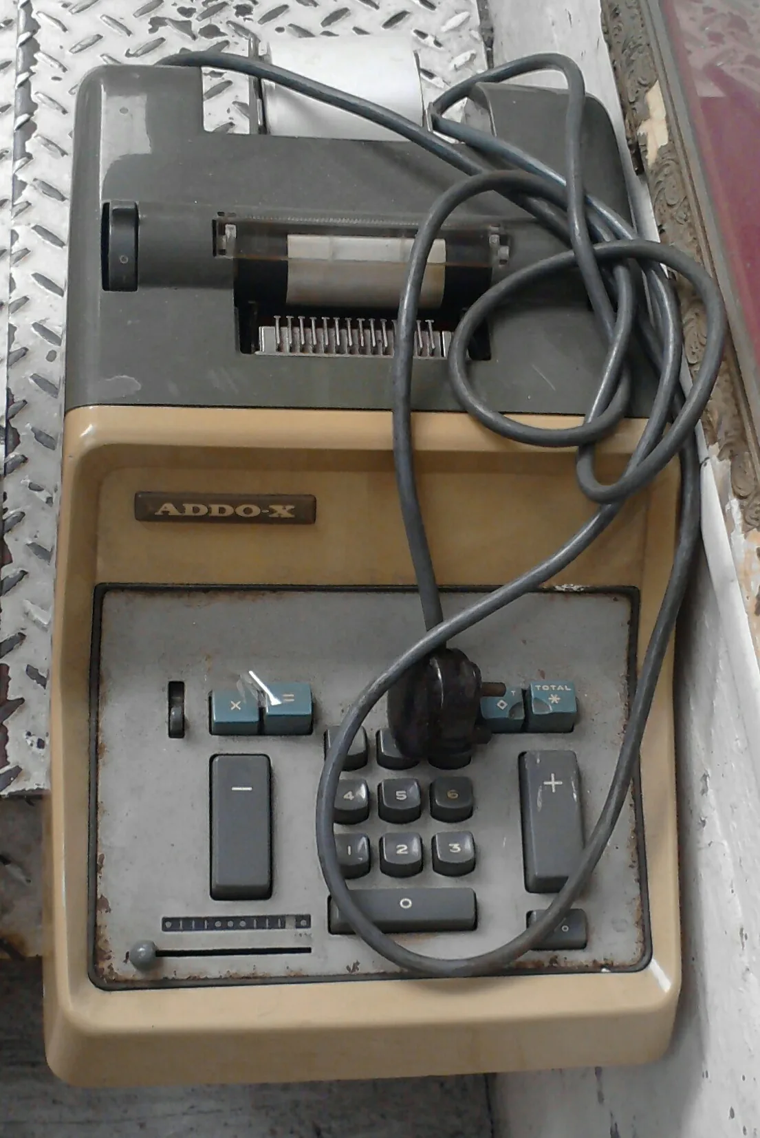 An adding machine with a paper tape rolled up, the keys and the total button in view