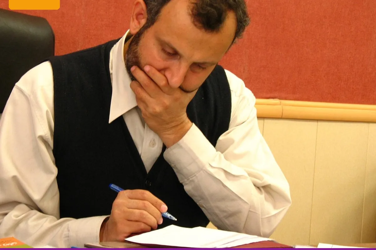 A person at a table reviewing a stack of papers before writing